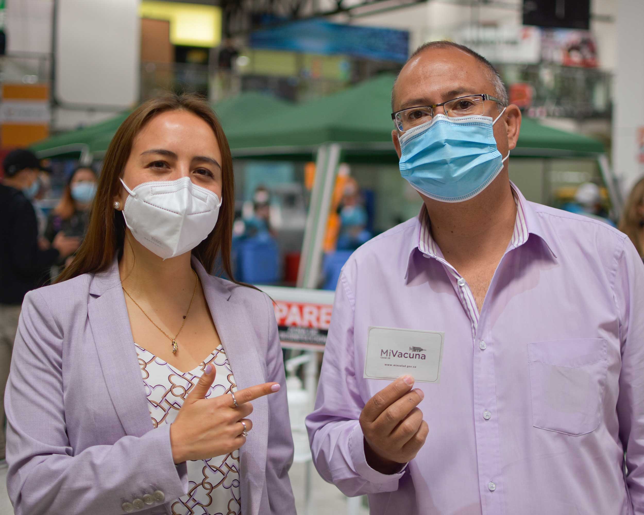 Stefanía Hernández junto a un conductor de taxi y su carnet en una jornada de vacunación.