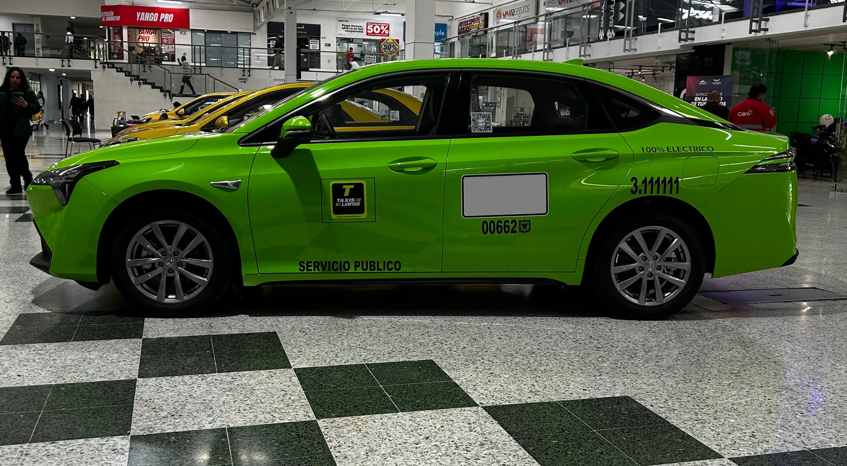 Vista lateral del taxi eléctrico AION ES de GAC con distintivos de Taxis Libres y servicio público