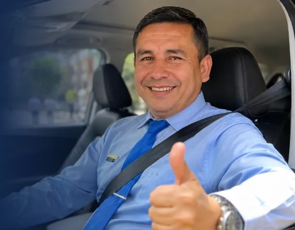Propietario de taxi sonriendo dentro de su vehículo Taxis Libres consultando la app de conductores. 
